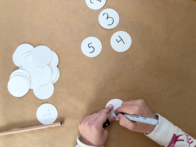 Child writing numbers on paper ornaments