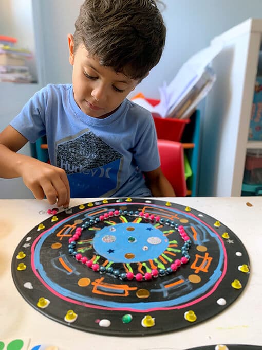 Boy-adding-sequins-to-record-mandala