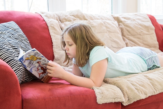 Girl reading graphic novels for summer reading.