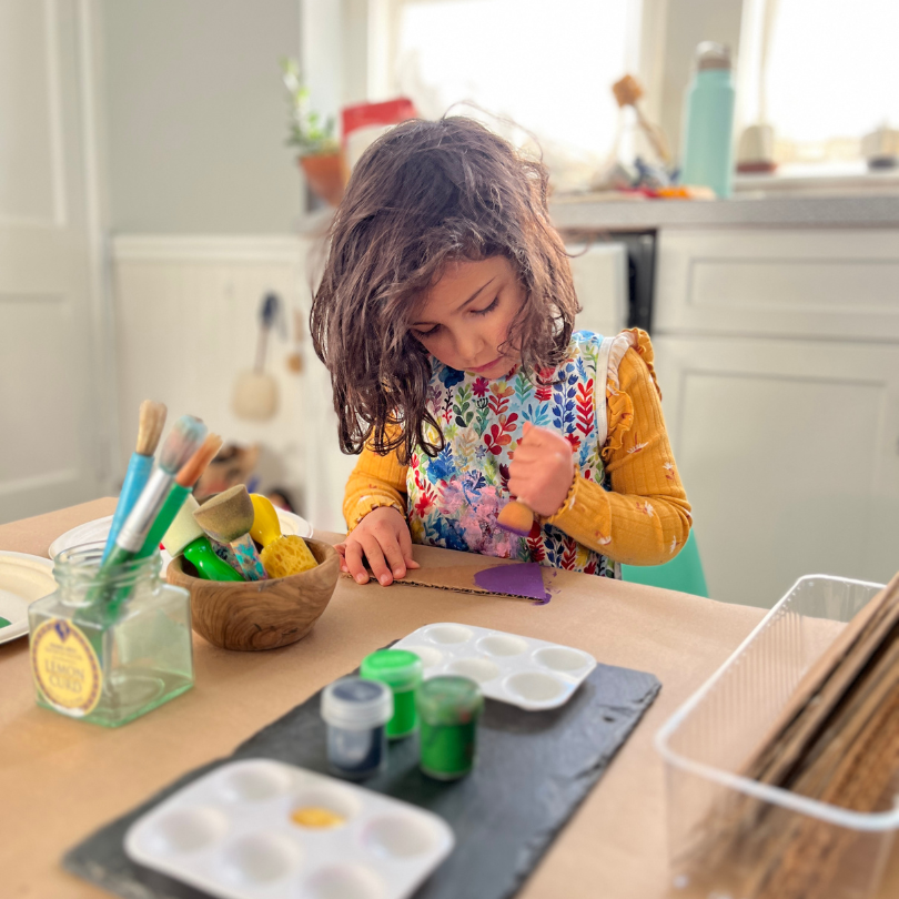 Child painting at kitchen table