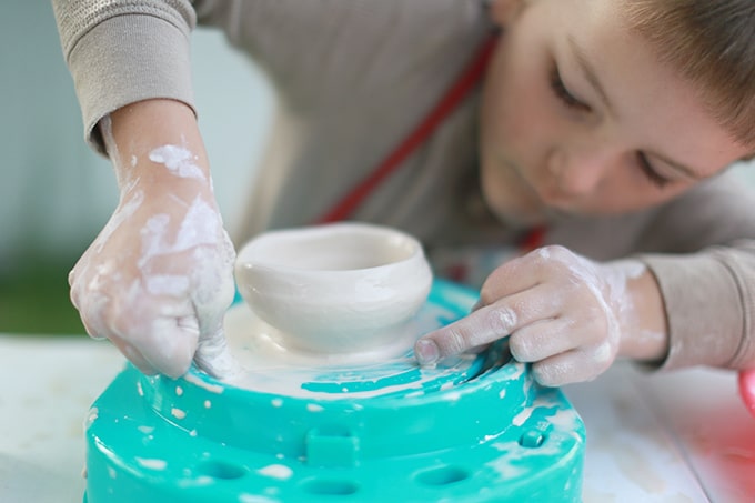 child cutting clay pot off kids pottery wheel